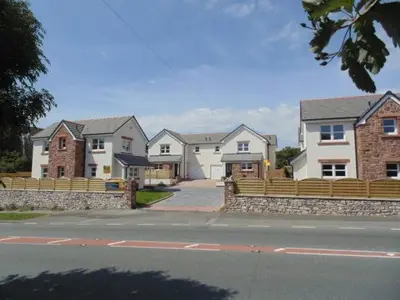 a row of houses with a fence on a street at Anchor Gardens Villa in Lindal in Furness