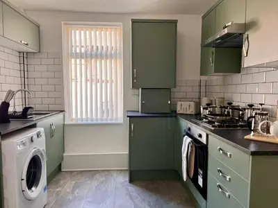 a kitchen with green cabinets and a washing machine at Spacious Home - Sleeps 5 persons - Minutes Walk from Anfield Stadium in Liverpool