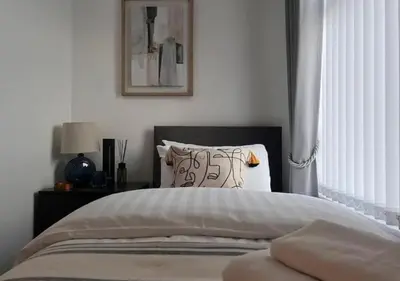 a bedroom with a bed with a black headboard and a window at Spacious Home - Sleeps 5 persons - Minutes Walk from Anfield Stadium in Liverpool