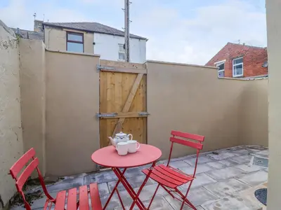 a red table and chairs on a patio with a gate at 49 Waddington Road in Clitheroe