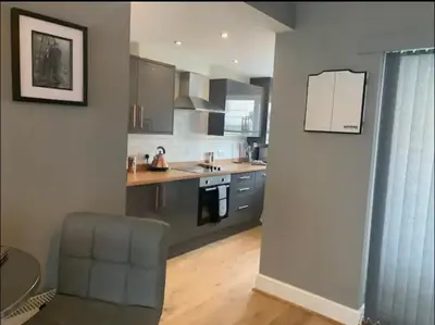 a kitchen with gray cabinets and a chair in a room at Seaside Suites in Blackpool