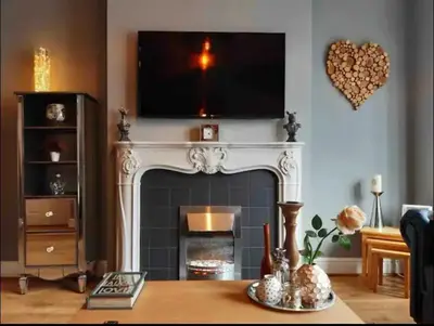 a living room with a fireplace with a tv above it at Seaside Suites in Blackpool