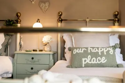a bedroom with a happy place pillow on a bed at Fern room at field view cottage in Eccleston