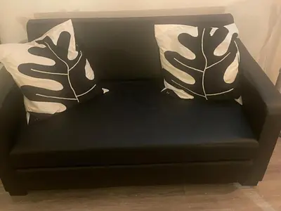 a black couch with two pillows on it at Manhattan Apartment City Centre sleeps 4 in Liverpool