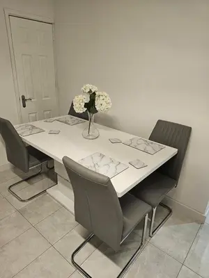 a table with chairs and a vase of flowers on it at Woolfall heath avenue in Roby