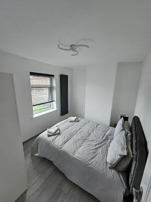 a white bedroom with a bed and a window at Woolfall heath avenue in Roby