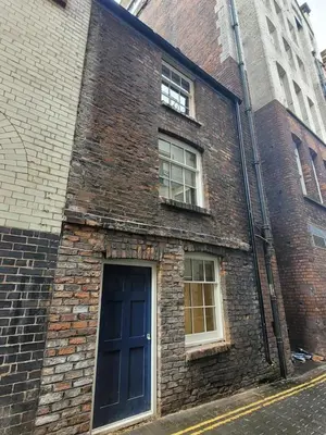 a brick building with a blue door and two windows at 10 Hockenhall - Liverpool's Oldest House in Liverpool