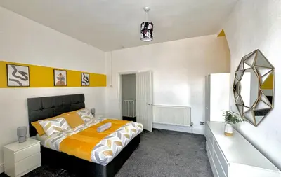 a bedroom with a large bed with orange and white sheets at No 6 - Home away from Home in Liverpool