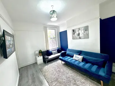 a living room with a blue couch and a window at No 6 - Home away from Home in Liverpool