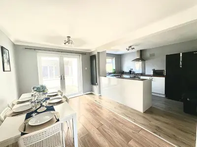 a kitchen and living room with a table and a dining room at Stunning Open Plan 3 Bed House - Driveway & Garden in Litherland
