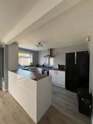 a large kitchen with white cabinets and a black refrigerator at Stunning Open Plan 3 Bed House - Driveway & Garden in Litherland