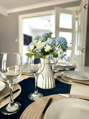 a table with a vase of blue and white flowers at Stunning Open Plan 3 Bed House - Driveway & Garden in Litherland