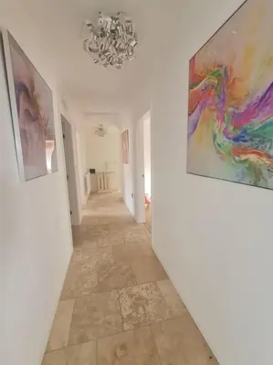 a hallway with paintings on the walls and a chandelier at 30 The Elms in Blackpool