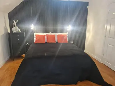 a bedroom with a black bed with orange pillows at 30 The Elms in Blackpool