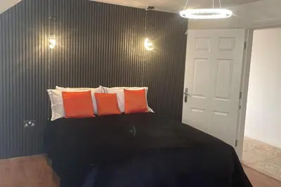 a bedroom with a black bed with orange and white pillows at 30 The Elms in Blackpool