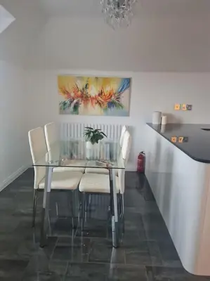 a dining room table with chairs and a painting on the wall at 30 The Elms in Blackpool