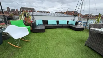 a rooftop patio with a couch and chairs on the grass at Float uniquely on Liverpool Waterfront on our high end 8 berth Houseboat in Liverpool