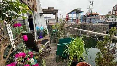 a patio with flowers and a boat in the water at Float uniquely on Liverpool Waterfront on our high end 8 berth Houseboat in Liverpool