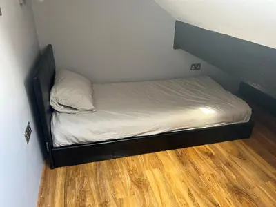 a small bed in a room with a wooden floor at Entire Seaside Home 6 Private BedRooms Sleeps 10,4 Minute Walk To Station in New Brighton