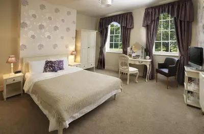 a bedroom with a bed and a desk and a television at Singleton Lodge Country House Hotel in Poulton le Fylde