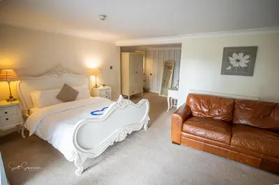 a bedroom with a large bed and a couch at Singleton Lodge Country House Hotel in Poulton le Fylde
