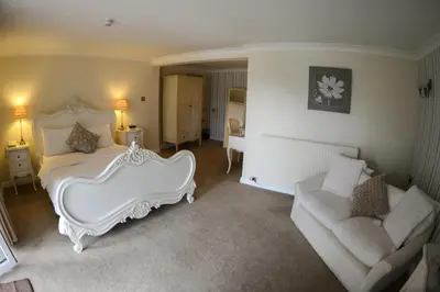a bedroom with a white bed and a couch at Singleton Lodge Country House Hotel in Poulton le Fylde