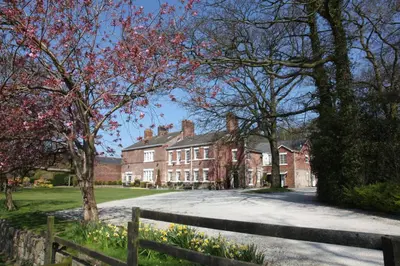 a large brick house with a fence in front of it at Singleton Lodge Country House Hotel in Poulton le Fylde
