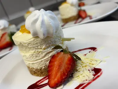a piece of cake with a strawberry on a white plate at Singleton Lodge Country House Hotel in Poulton le Fylde