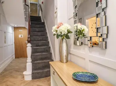 a vase with flowers on a table in a hallway at 7-Bed Beachside Retreat - Sleeps 14 & Pet Friendly in Blackpool