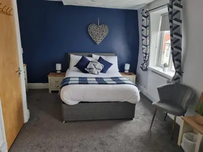 a bedroom with a bed with a blue wall at 7-Bed Beachside Retreat - Sleeps 14 & Pet Friendly in Blackpool