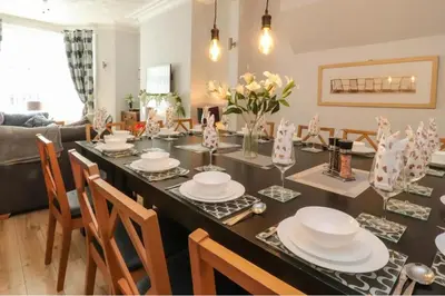 a dining room with a table with plates and chairs at 7-Bed Beachside Retreat - Sleeps 14 & Pet Friendly in Blackpool
