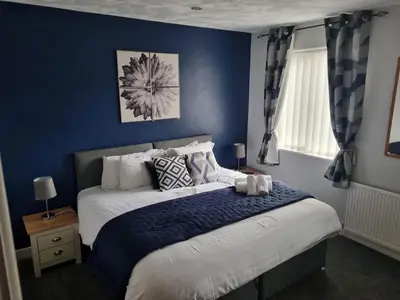 a bedroom with a bed with a blue wall at 7-Bed Beachside Retreat - Sleeps 14 & Pet Friendly in Blackpool