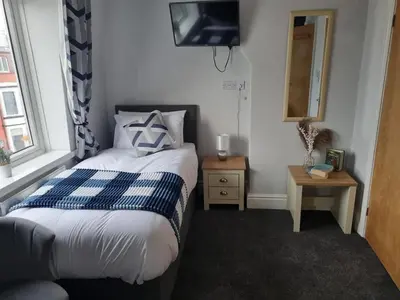 a small bedroom with a bed and a television at 7-Bed Beachside Retreat - Sleeps 14 & Pet Friendly in Blackpool