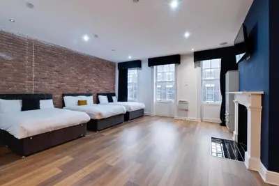 a bedroom with two beds and a brick wall at 9 Rodney Townhouse in Liverpool