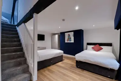 a bedroom with two beds and a staircase at 9 Rodney Townhouse in Liverpool