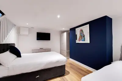 a bedroom with two beds and a blue wall at 9 Rodney Townhouse in Liverpool