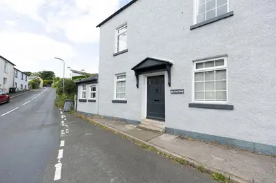 a white house with a door on the side of a street at OLD BANK HOUSE - Perfect Getaway for Friends & Families in Holker
