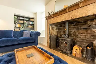 a living room with a blue couch and a fireplace at OLD BANK HOUSE - Perfect Getaway for Friends & Families in Holker