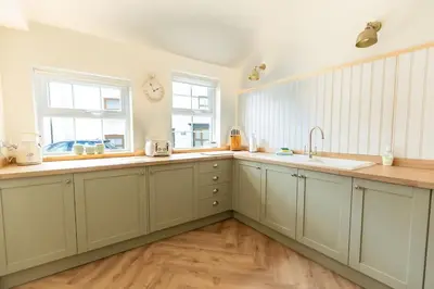 a kitchen with white cabinets and a sink and two windows at OLD BANK HOUSE - Perfect Getaway for Friends & Families in Holker