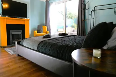 a bedroom with a bed and a table and a television at Detached Homestay - Super, King & Double Rooms - Leyland, Preston, Chorley, Lancashire in Leyland