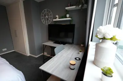 a living room with a table and a television at Detached Homestay - Super, King & Double Rooms - Leyland, Preston, Chorley, Lancashire in Leyland