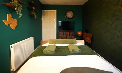 a bedroom with a large bed with green walls at Detached Homestay - Super, King & Double Rooms - Leyland, Preston, Chorley, Lancashire in Leyland