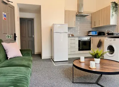a living room with a green couch and a kitchen at Apartment 1 in Blackpool