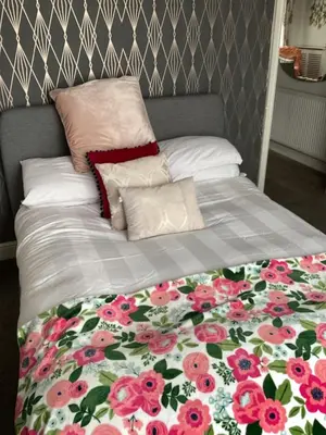 a bed with a floral blanket and pillows on it at 2 bedroom apartment in Horwich