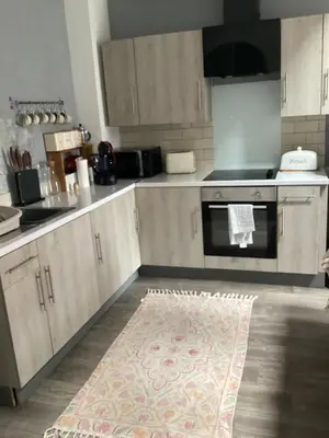 a kitchen with wooden cabinets and a rug on the floor at 2 bedroom apartment in Horwich