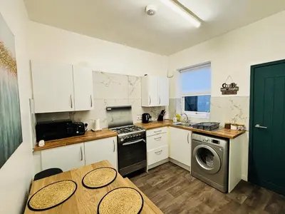 a kitchen with white cabinets and a table and a washer at ENTIRE LUXURY HOUSE near CITY CENTRE - FREE PARKING in Liverpool