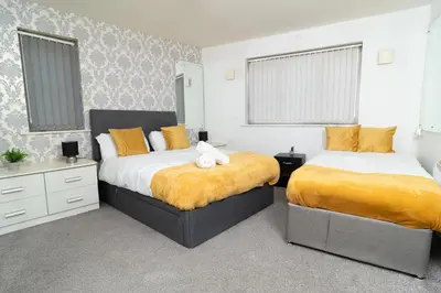 two beds in a bedroom with yellow and white at City Haven Modern 3 Bedroom Apartment with Private Parking in Liverpool