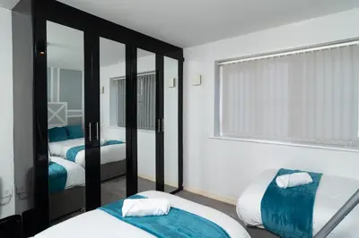 a bedroom with two beds and a mirror at City Haven Modern 3 Bedroom Apartment with Private Parking in Liverpool
