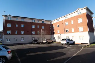 a parking lot with cars parked in front of a building at City Haven Modern 3 Bedroom Apartment with Private Parking in Liverpool