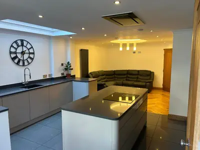 a kitchen and living room with a couch and a clock at Entire Seaside Home 6 Private Bedrooms Sleeps 10 in Wallasey